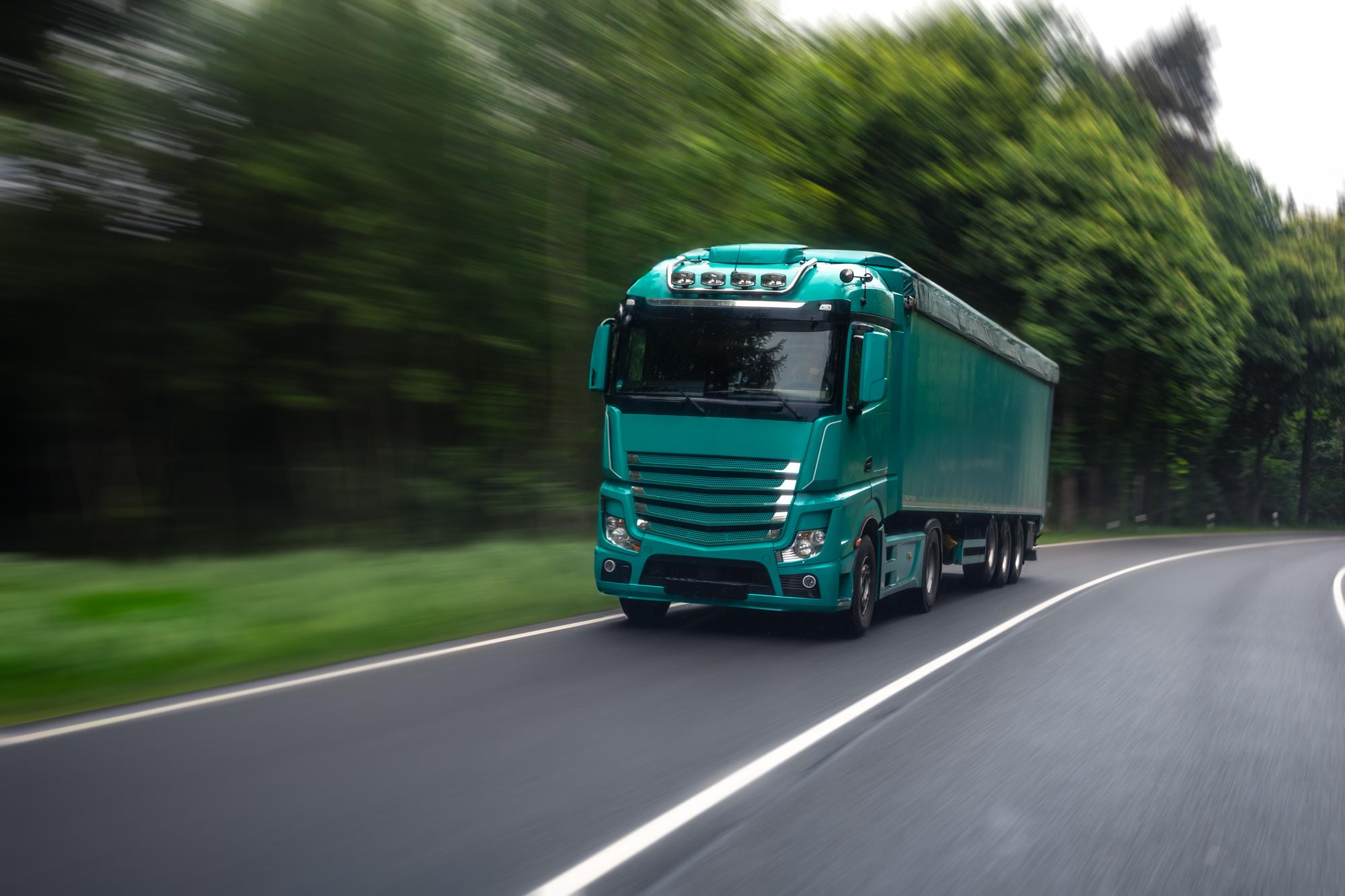 Ciągnik siodłowy Mercedes-Benz Actros z czerwoną naczepą kurtynową.